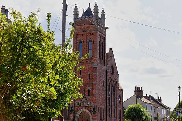 istock A church with a tall steeple is partially obscured by a tree. 2221512534