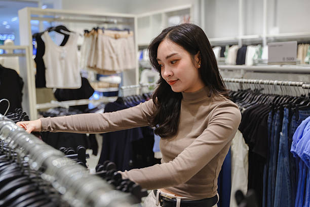 istock Customer browsing through clothing racks in a retail store, thoughtfully selecting garments and enjoying the shopping experience 2221515779