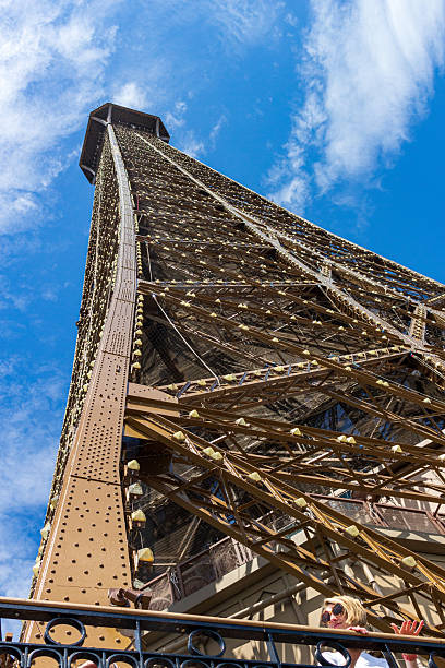 istock A low-angle shot captures the Eiffel Tower stretching high into a blue sky with scattered clouds. 2221516331