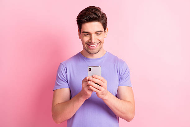 istock Portrait of nice cheerful focused guy holding in hand using device chatting 5g isolated over pink pastel color background 2221516581