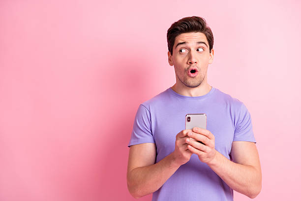 istock Portrait of nice amazed guy using device looking aside copy space pout lips ad isolated over pink pastel color background 2221516740