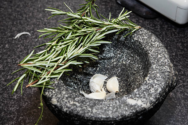 Fresh rosemary and garlic cloves ready to be grinned in a mortar