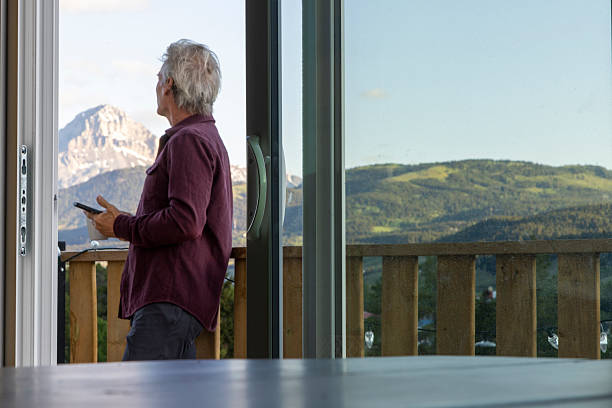 istock View through doorway to mature man on deck with mobile phone 2221521448
