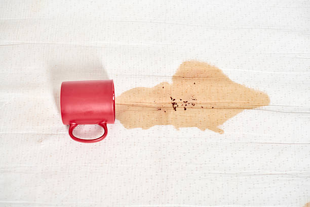 Red mug spills coffee on white fabric, creating stain