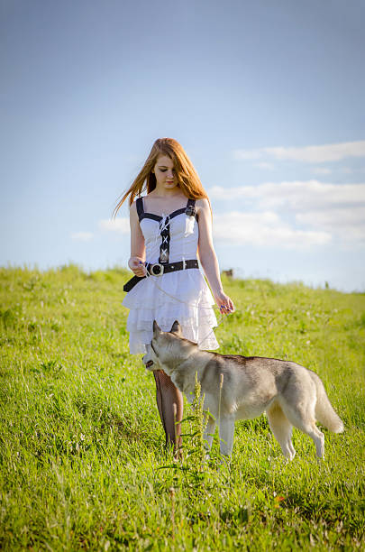 istock Young woman with husky on sunny field 2221529675