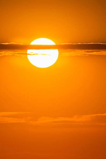 istock Golden sun glowing through thin clouds in vibrant orange sky at sunrise or sunset, creating a warm, dreamy atmosphere 2221537844