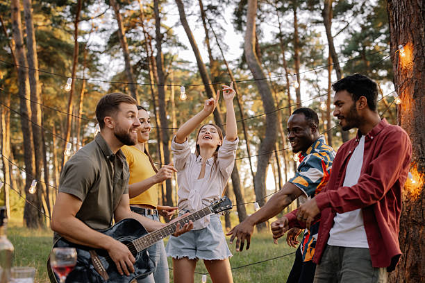 istock Friends playing guitar and dancing at a forest party 2221538433