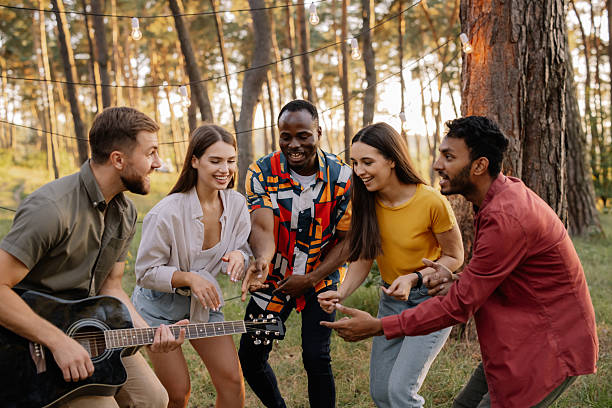 istock Interracial friends singing and playing guitar at a forest party 2221538437
