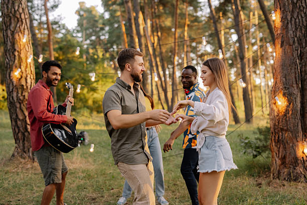 istock Interracial friends dancing and playing music in a forest at sunset 2221540697