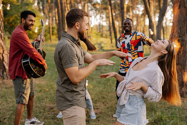 Interracial friends dancing and playing music at a forest party