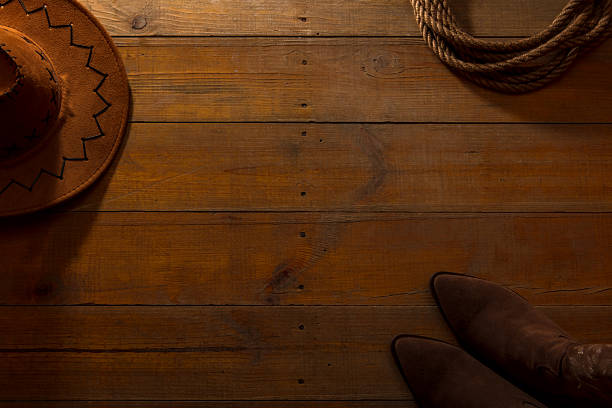 Lasso, cowboy hat and boots on barn wood texture background. American wild west concept. Space for copy.