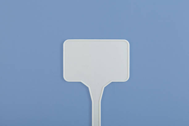 Empty plastic sign as design element. White plant stake on blue background.