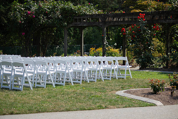 istock Wedding ceremony setup with white chairs arranged in a beautiful garden location surrounded by blooming flowers 2221550093