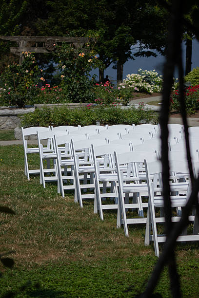 istock Wedding ceremony setup with white chairs arranged in a beautiful garden location surrounded by blooming flowers 2221550146
