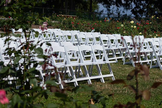 istock Wedding ceremony setup with white chairs arranged in a beautiful garden location surrounded by blooming flowers 2221550152