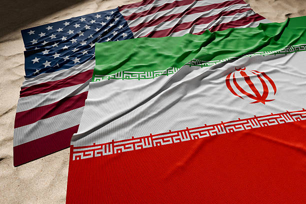 istock American And Iranian Flags Resting on Desert Sand. 2221552207