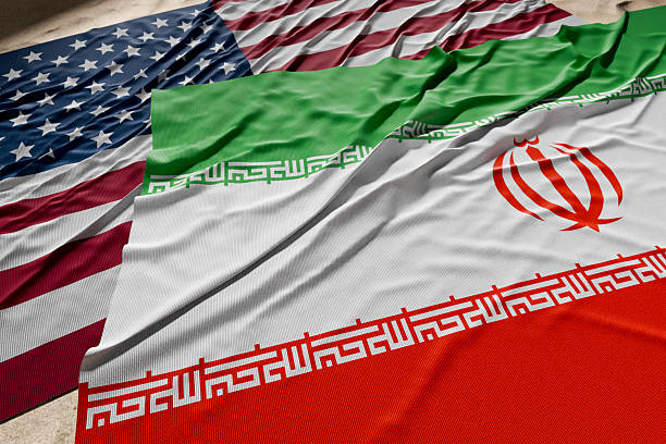 istock American And Iranian Flags Resting on Desert Sand. 2221552215