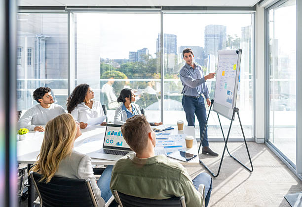istock Business people watching a presentation on the whiteboard. A man is writing on the whiteboard with charts and graphs. 2221552556