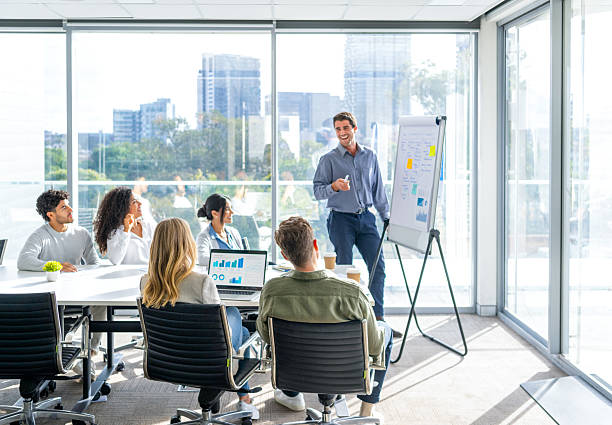 istock Business people watching a presentation on the whiteboard. A man is writing on the whiteboard with charts and graphs. 2221552614