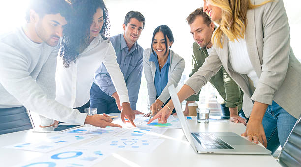 istock Financial and business documents on table with multiethnic group of people working on them. 2221552694