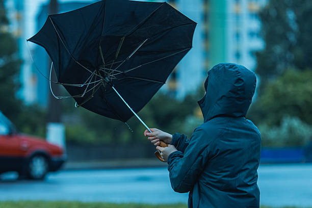 man with umbrella hiding from wind and rain. stormy weather - yağmur firtina stok fotoğraflar ve resimler