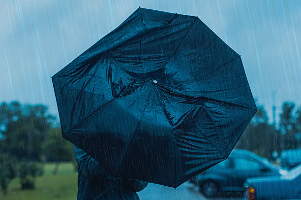 istock Man with umbrella hiding from wind and rain. Stormy weather 2221556246