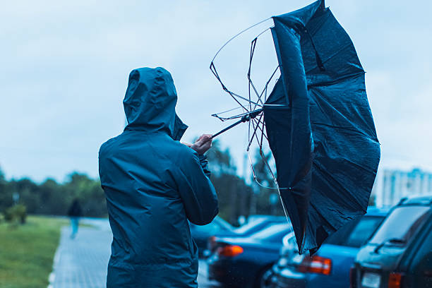 Man with umbrella hiding from wind and rain. Stormy weather