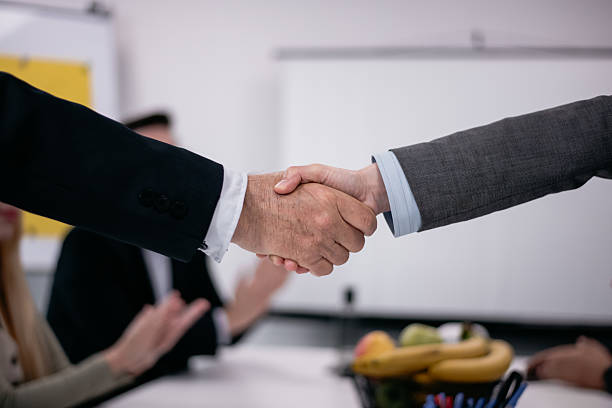 istock Professional handshake symbolizing agreement with people in a business setting 2221564424