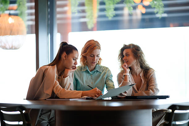 istock Three professional women collaborate on a project at a large table, reviewing documents and planning strategy during a meeting in the modern office 2221564512