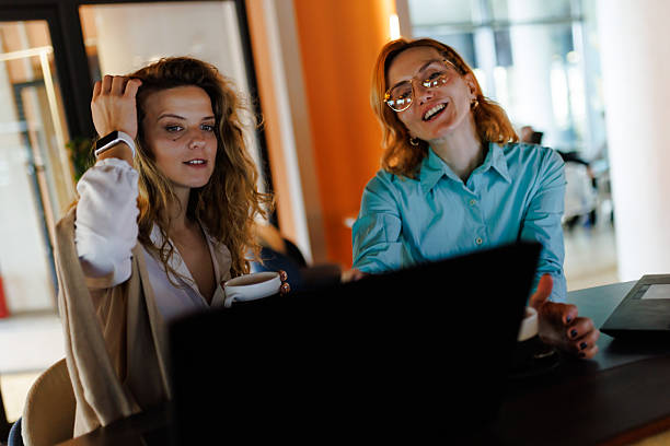 istock Businesswomen collaborating in a modern office space over coffee while working on a laptop during a productive morning meeting 2221564518