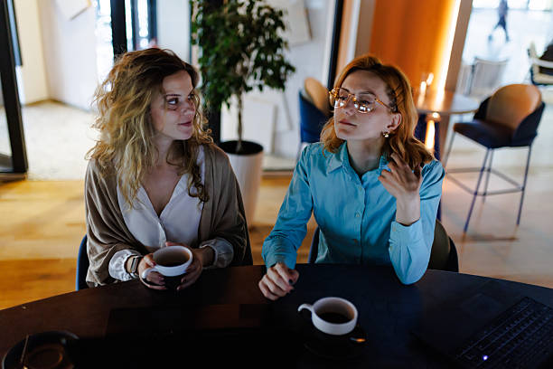 istock Business discussion between two women in a modern workspace with coffee cups in hand during a bright afternoon 2221564594