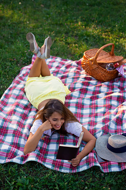 istock Young woman reading book on the summer picnic 2221576736