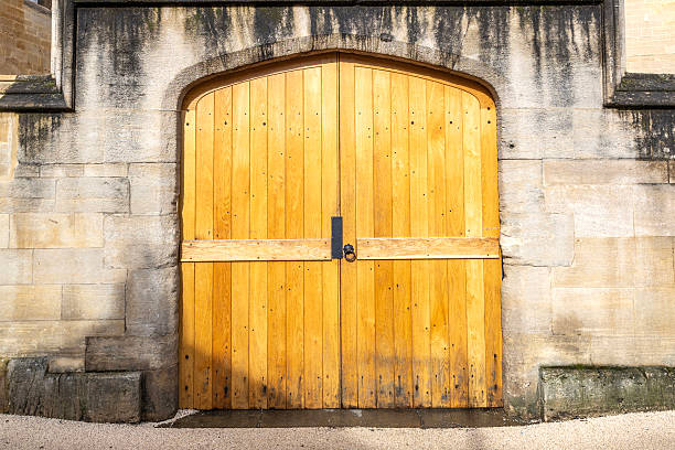 A brightly lit large wooden door entrance to a old stone building in Oxford, England