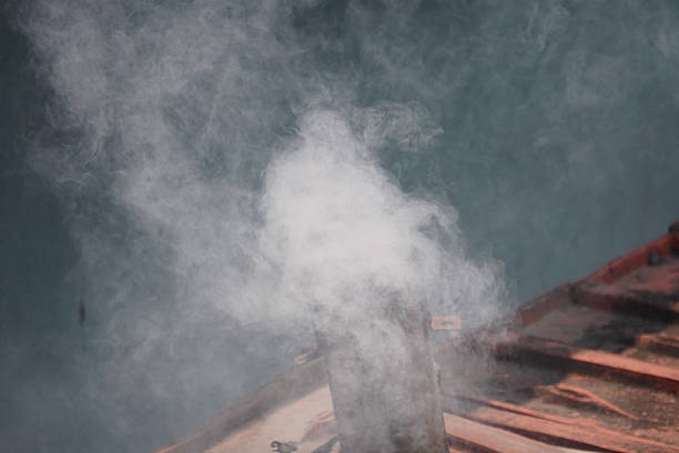 White Smoke Rising from Wooden Platform Beside Blue-Green Water Surface