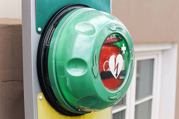 istock Public defibrillator green box. Emergency AED mounted on building wall. Medical help access. Life-saving equipment outdoors. 2221594713
