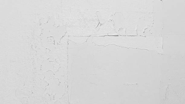istock Close up view of a distressed white concrete wall with cracking and peeling paint, creating a textured and aged backdrop perfect for design projects 2221596286