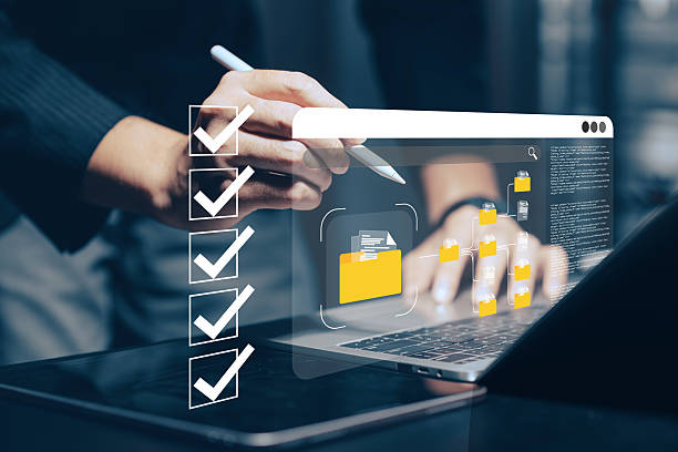 Digital document management and workflow automation: A hand uses a stylus on a tablet, with a laptop in the background, interacting with a holographic checklist and various digital document icons representing efficient online processes, task completion.