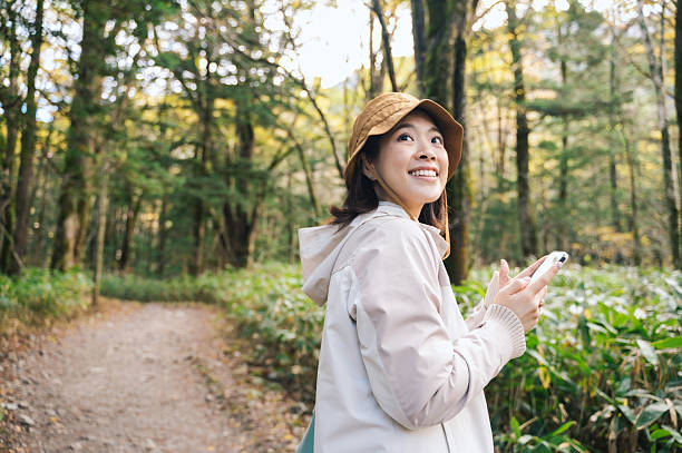 istock smiling young woman using mobile phone in lush forest symbolizing emotional technology and future of social computing outdoors at Kamikochi national park Japan 2221604089