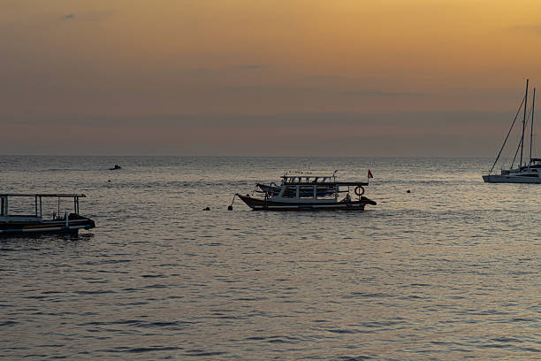 Tranquil ocean seascape featuring various boats under a soft golden hour sky during dusk