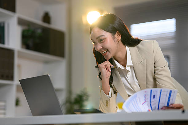 istock Confident female office worker leaning over desk, analyzing data on her laptop 2221604991