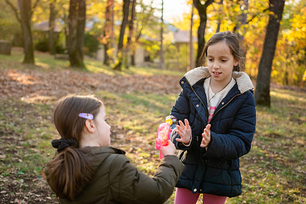 Two happy girls playing whit bubbles at the park