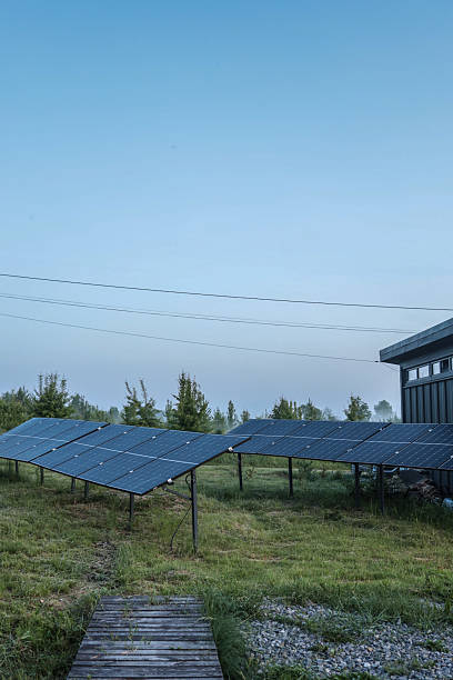 istock Solar panel installations beside a modern utility building in a green field, generating renewable energy on a sunny day 2221609045