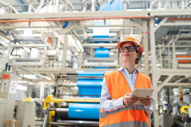 istock Engineer overseeing operations on tablet in bright industrial plant wearing safety gear. 2221613201