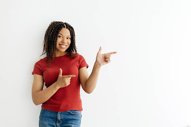 istock Young African American woman smiling while pointing aside with both hands 2221615196
