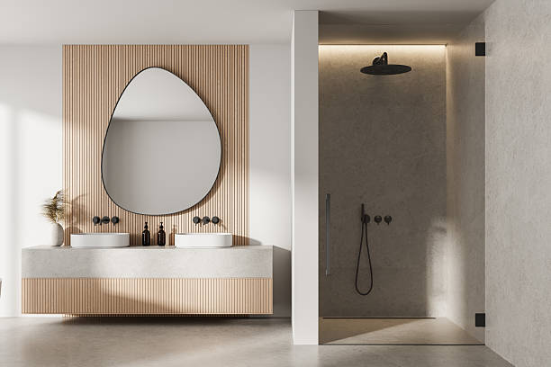 istock Modern minimalist bathroom interior with wood panel wall, asymmetrical mirror, dual sinks, and walk-in stone shower under warm ambient lighting. 3D Rendering 2221615431