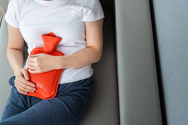 Woman holding orange hot water bottle on sofa