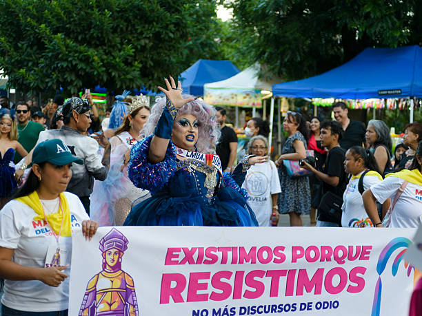 A vibrant LGBTQ+ pride parade unfolds, showcasing drag queens, protestors, and a banner reading 'Existimos Porque Resistimos' (We Exist Because We Resist). stock photo