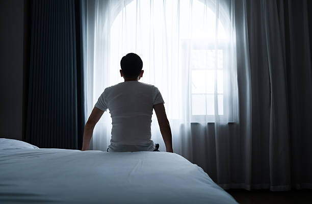 istock Rear view of a man sitting on bed 2221616528