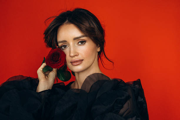 istock Timeless Beauty Holding a Rose Against a Bold Red Canvas 2221616596
