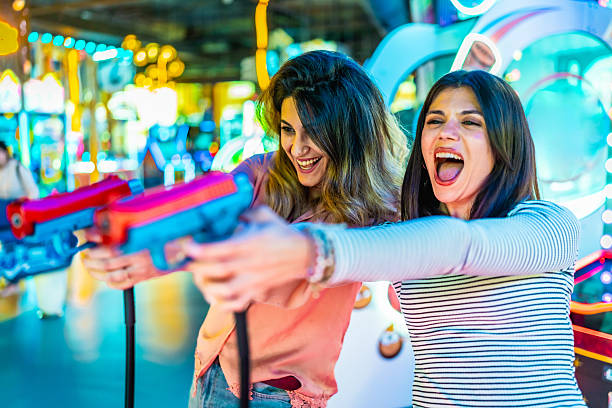 istock Two young women playing arcade shooting game together 2221617207